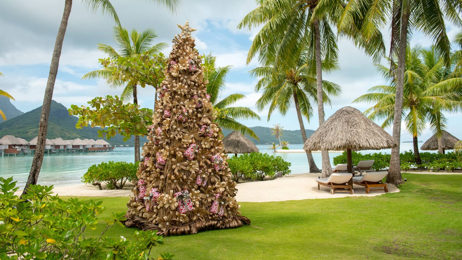 Decorative Christmas tree on resort lawn surrounded by palm trees