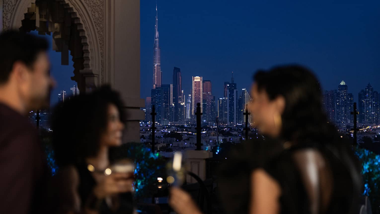 Friends mingle at a Dubai hotel rooftop bar with Dubai skyline view