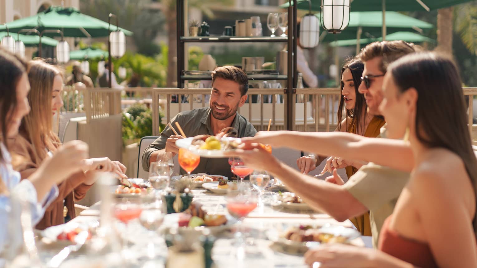 Six people sit at an outdoor table for brunch on a sunny day