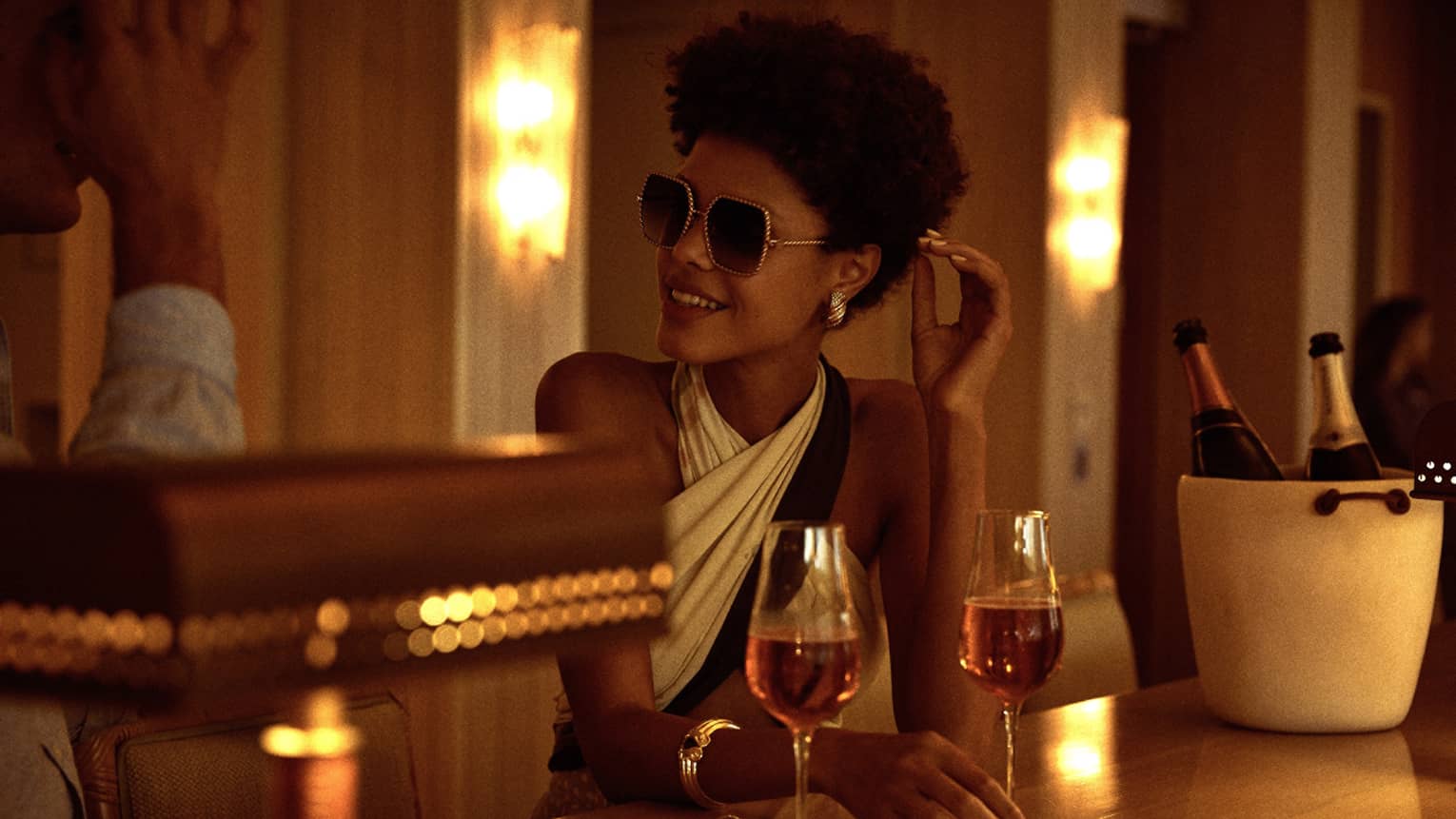 A woman sitting a dimly lit bar with a glass of wine.