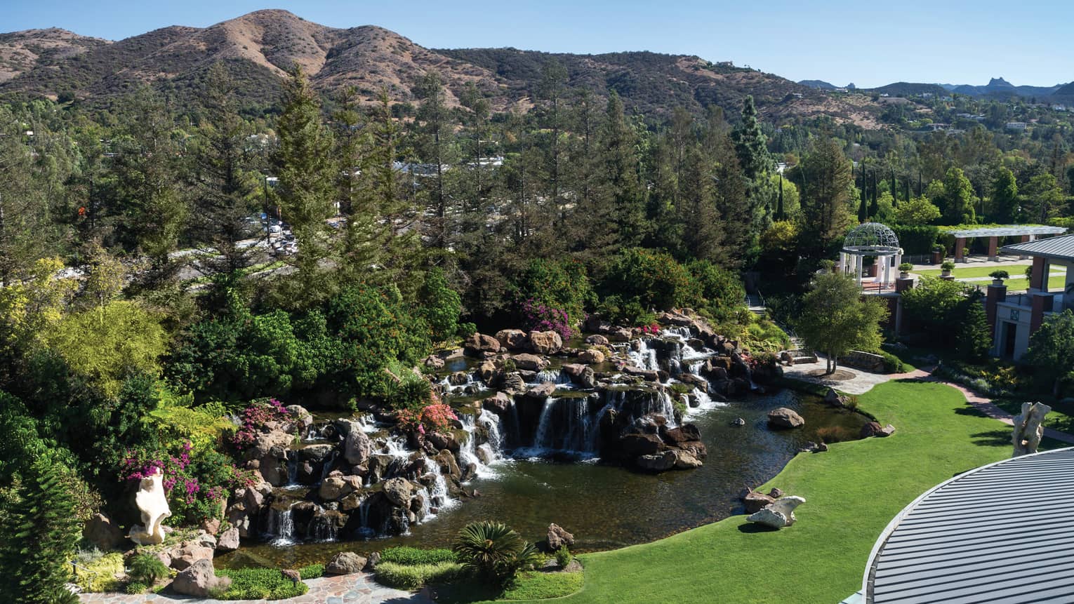 of rocks, waterfalls in front of forest, rolling green hills