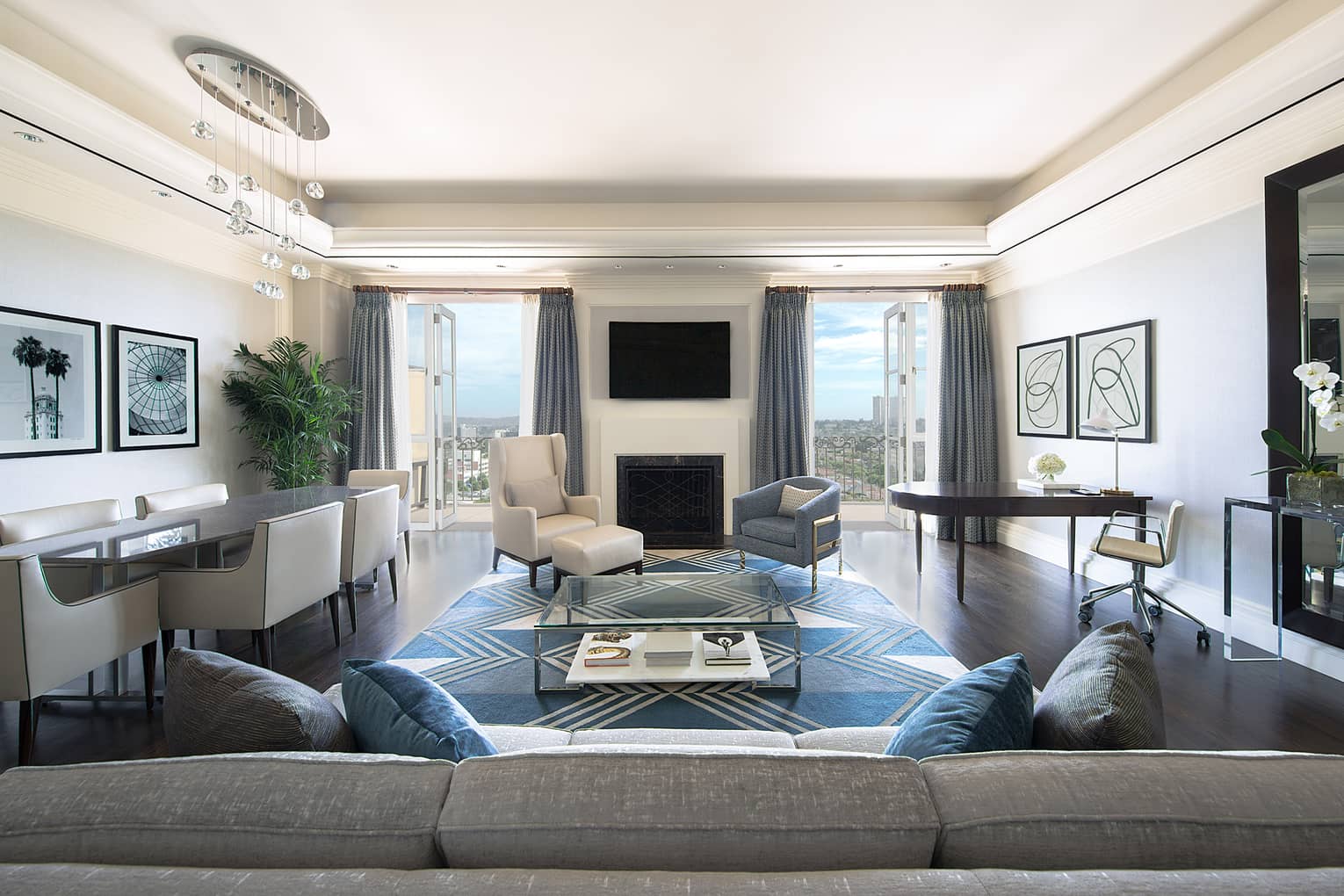 Ambassador Suite back of long sofa, dining table, armchairs by fireplace, TV, open balcony doors