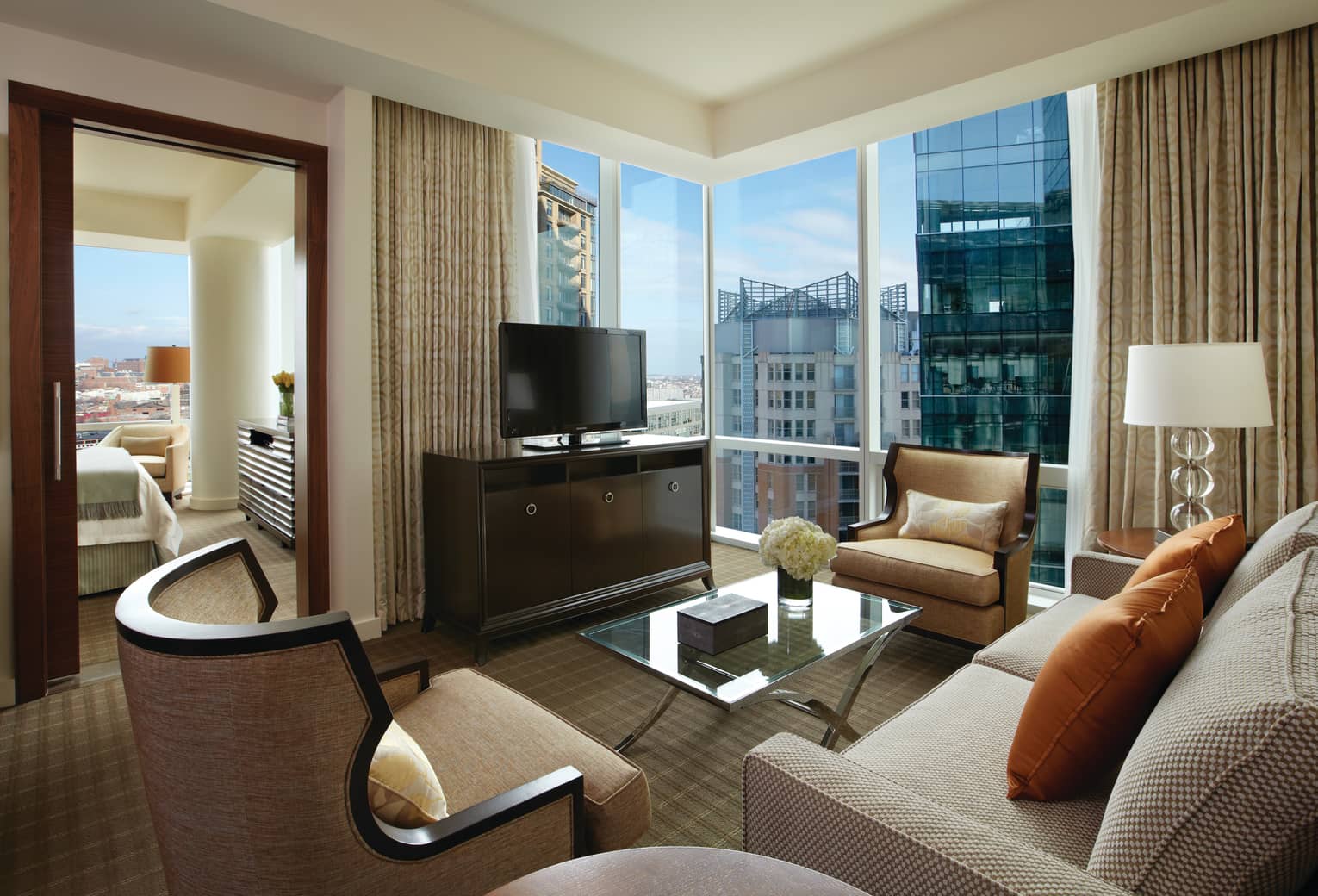Executive Suite living room sofas, chairs, TV, corner glass windows