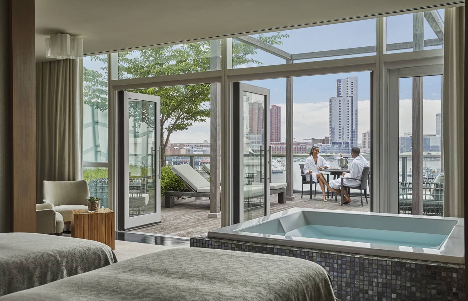 Spa Suite treatment beds and tub by open wall to sunny patio where couple sits