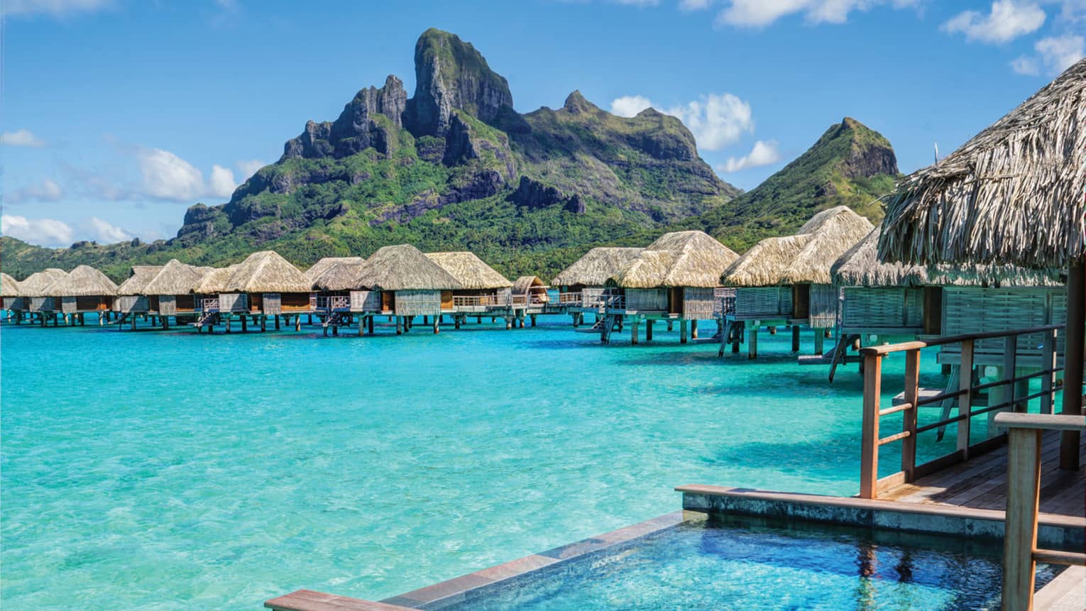Indoor-outdoor design of overwater bungalow deck, with plunge pool over turquoise lagoon