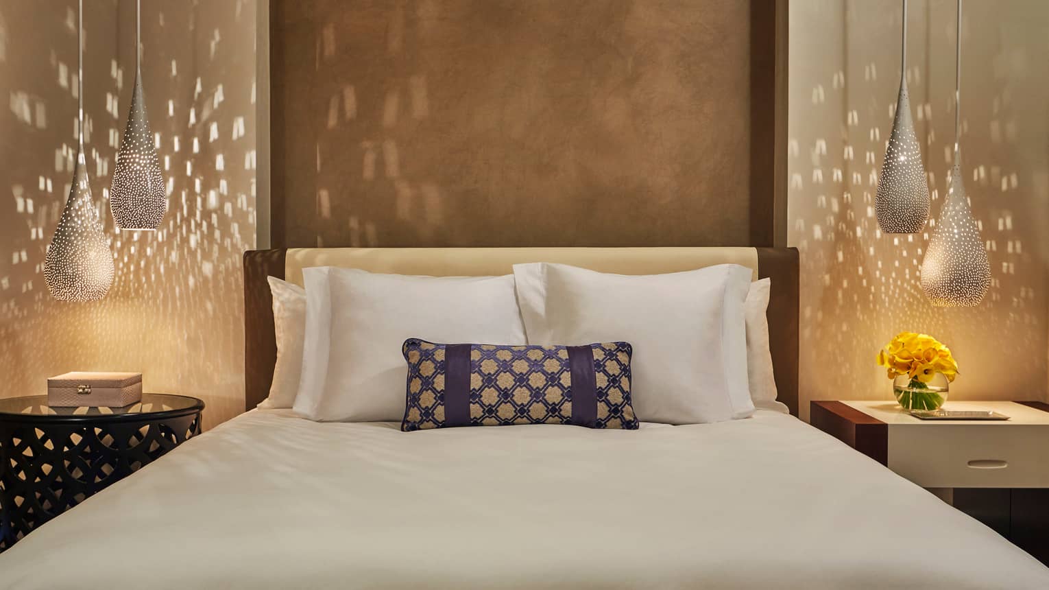 Reflection of light from teardrop lamps on wall beside bed