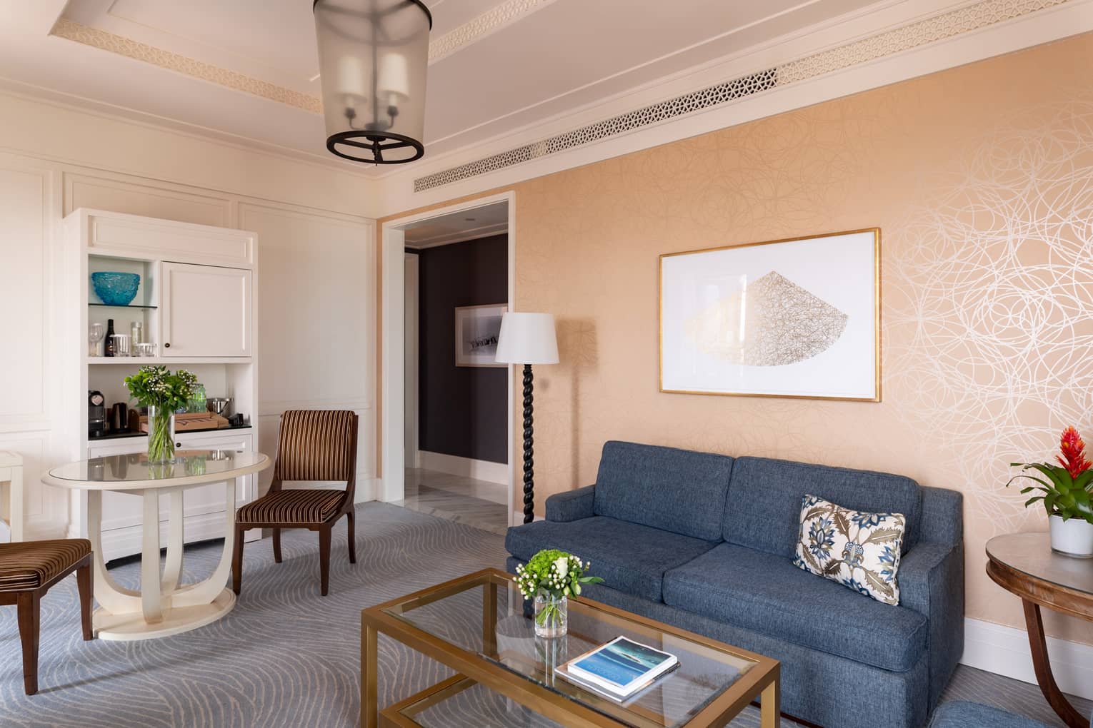 Living room with salmon-coloured wallpaper, small blue sofa, grey carpet, table