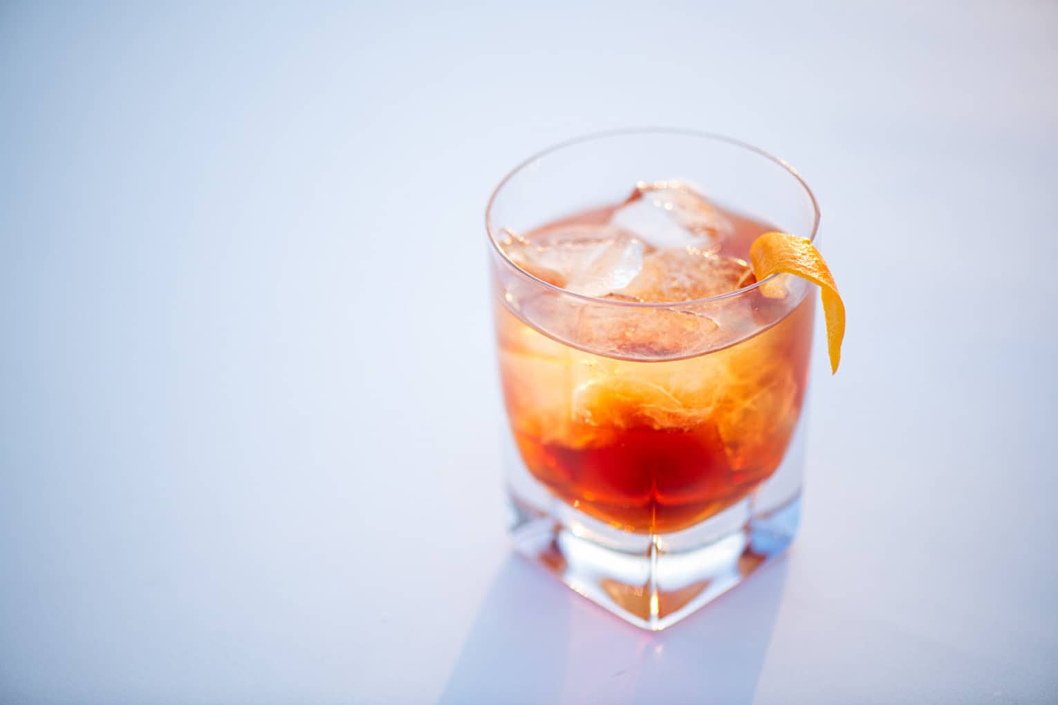 A blood orange cocktail in a whiskey glass and topped with an orange slice.