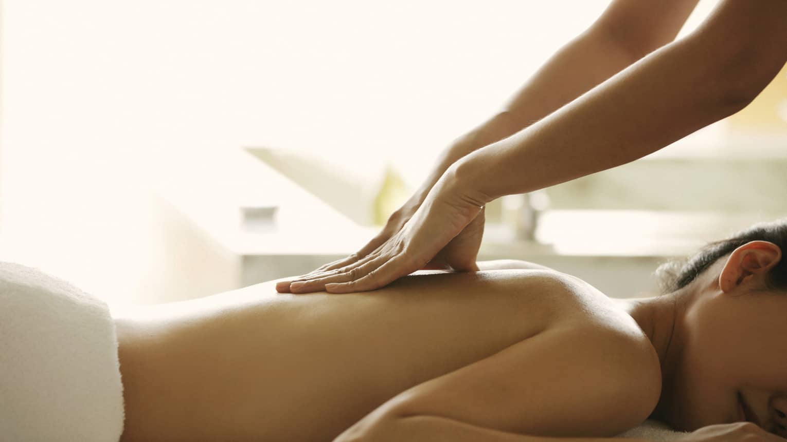 Close-up of a person receiving a relaxing back massage in a spa setting.