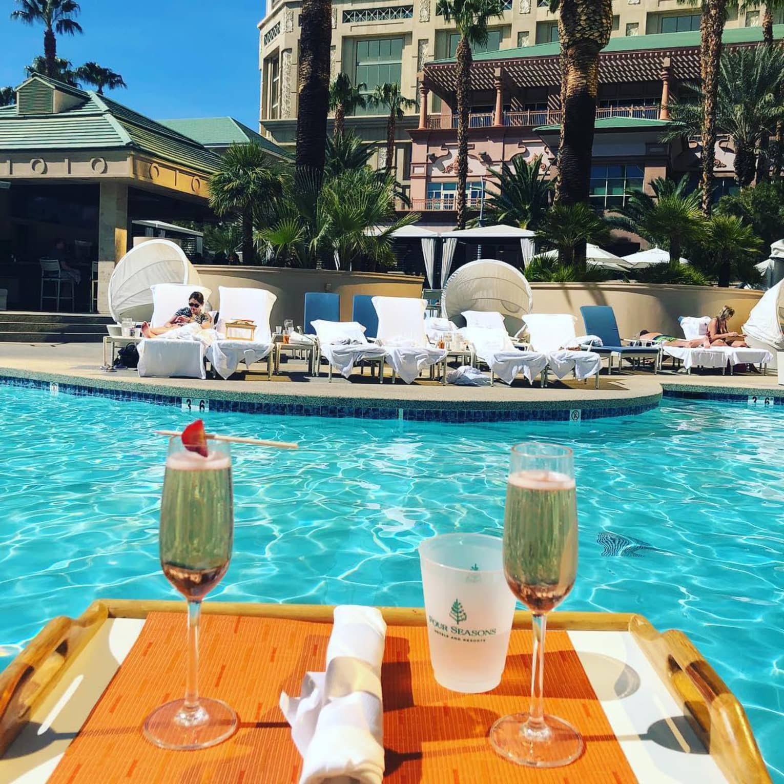 Two glasses of Champagne on tray floating in outdoor swimming pool