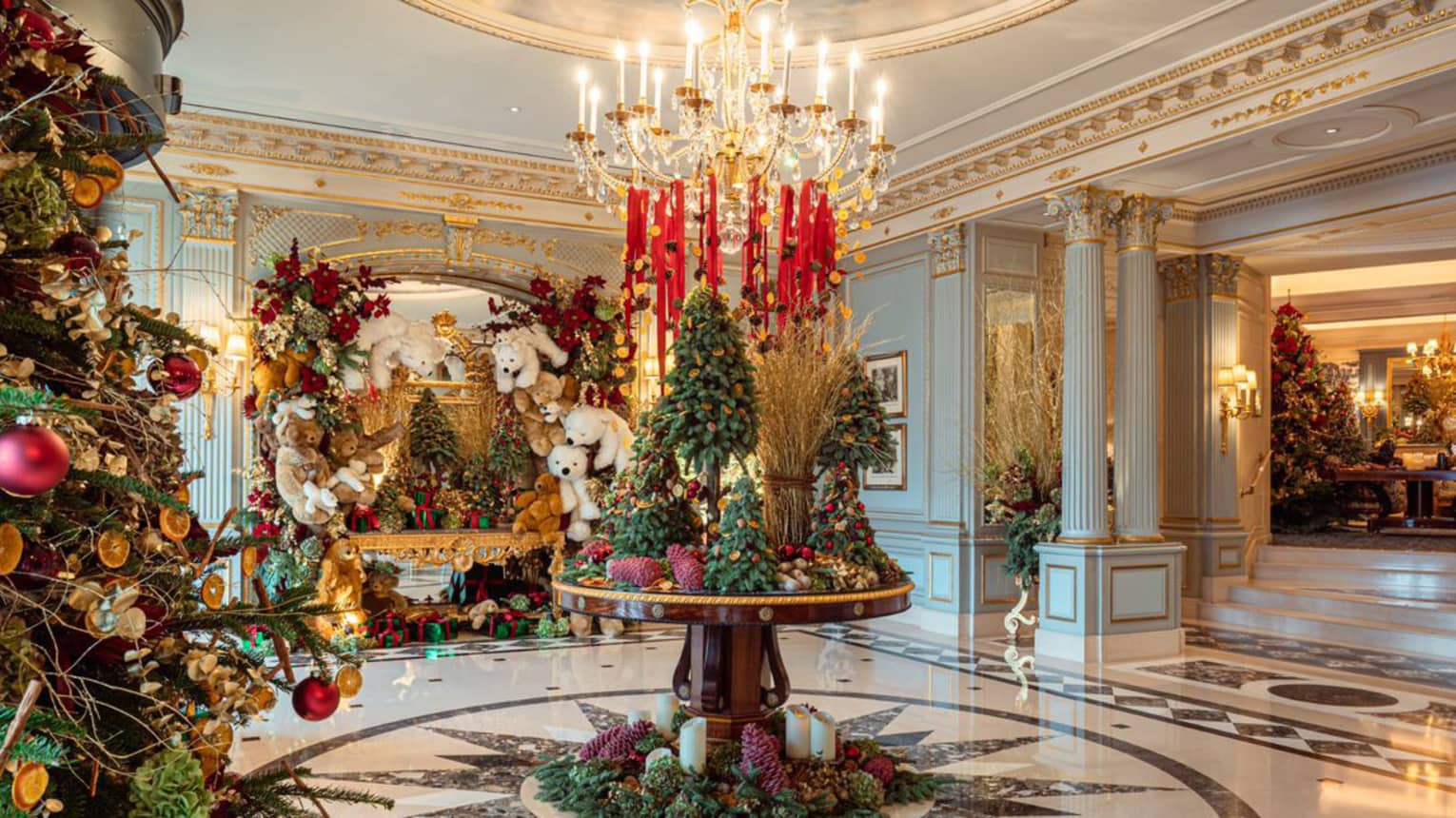 Elegant hotel lobby circular table topped with Christmas tree d�cor under a crystal chandelier