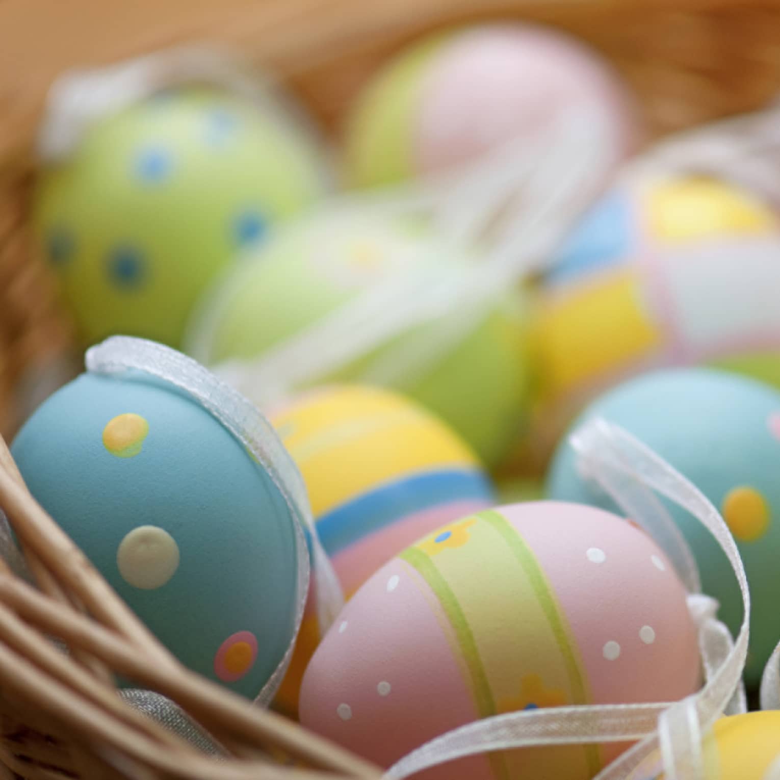 A basket of blue, pink, green and yellow colourful Easter eggs.