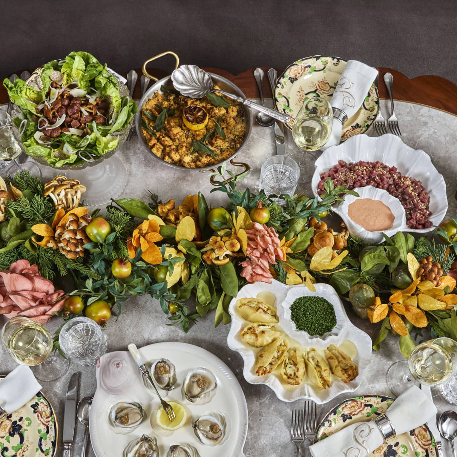 Many food dishes including clams and a salad bowl along with a table centrepiece.