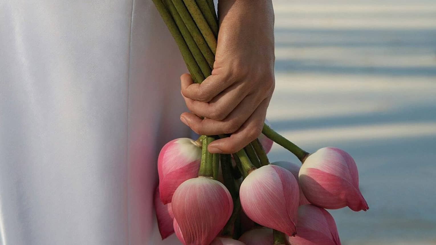 Bride holds wedding bouquet with long stemmed pink flowers