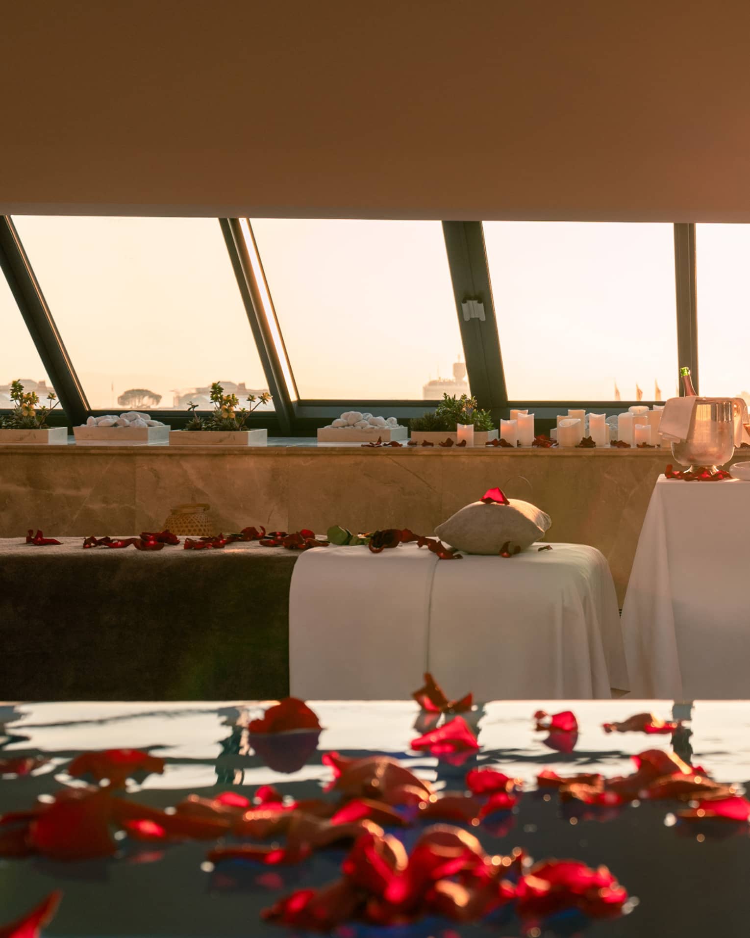 Spa pool sprinkled with red rose petals and couples spa tables poolside with skylight views