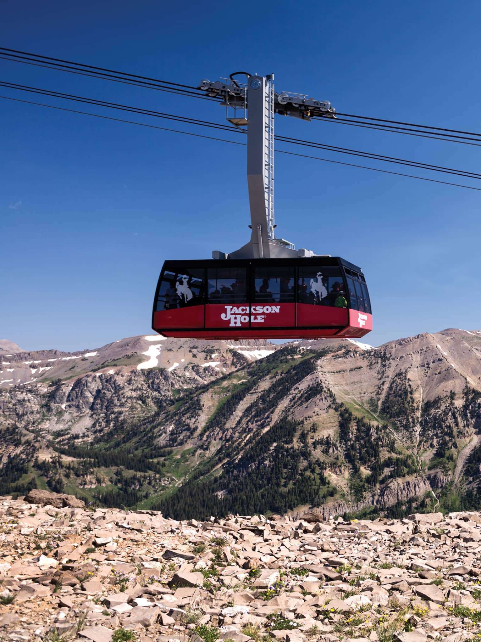 A family of four watches from a cliff as a ski lift passes by