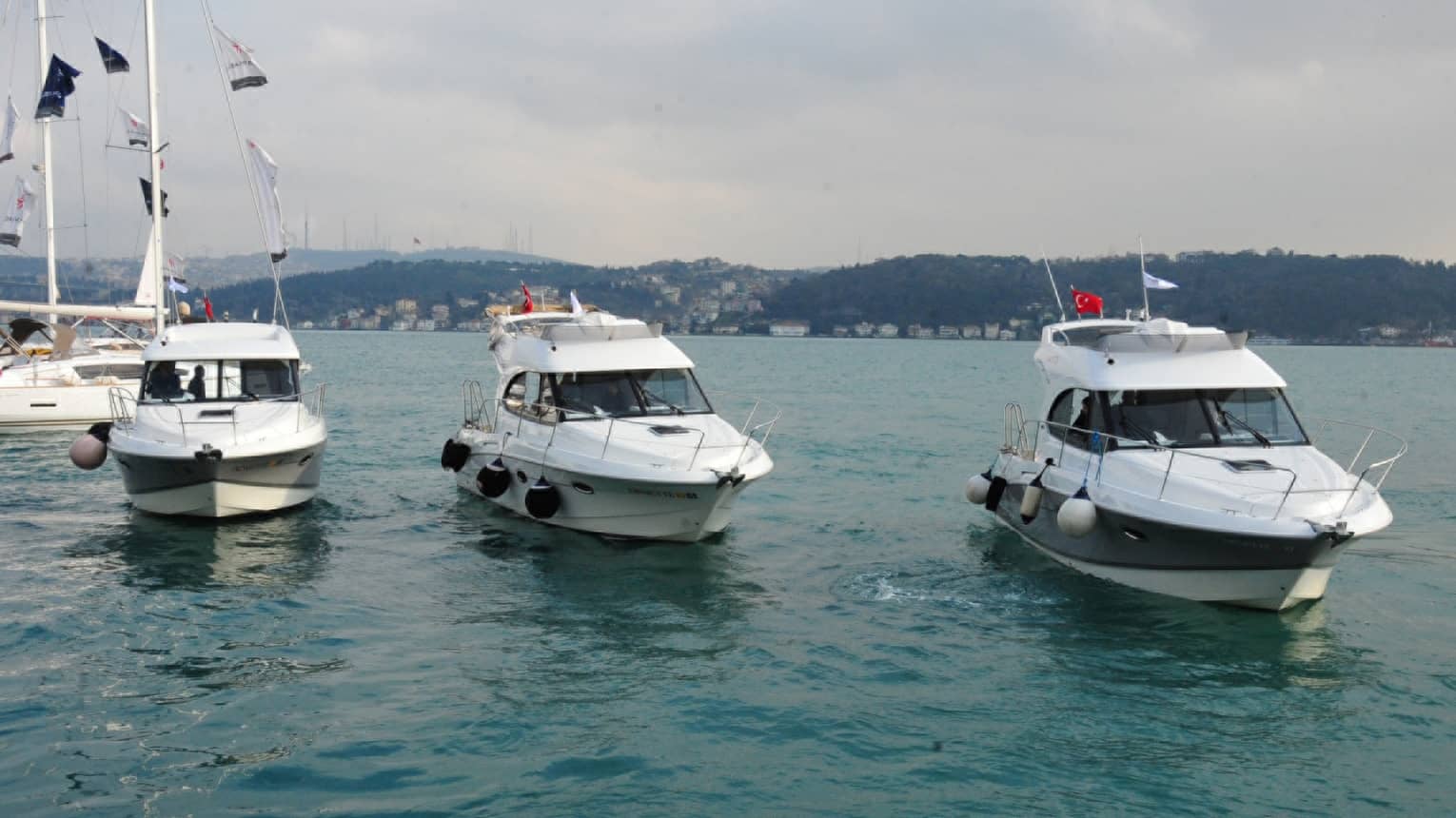 Three small white yachts parked on the Bosphorus 