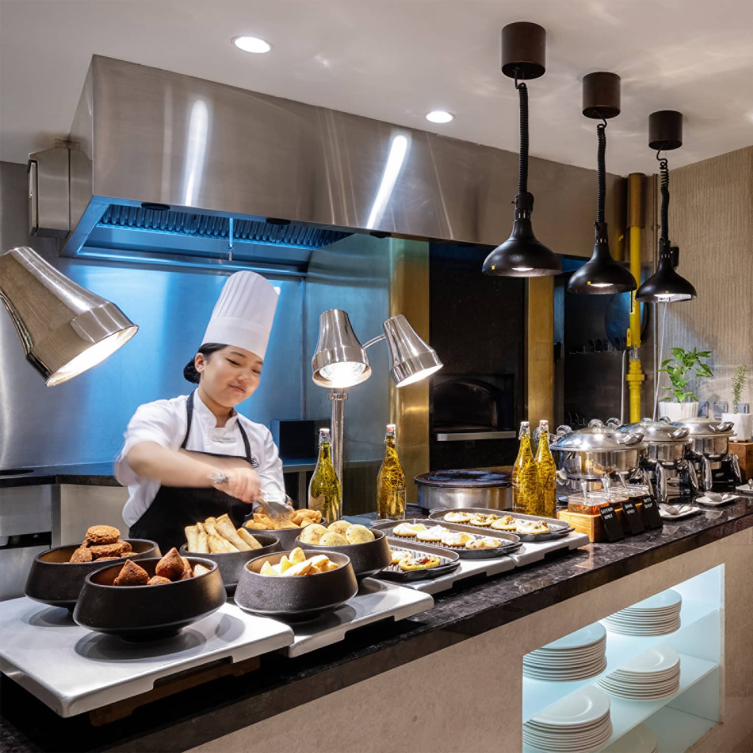 Breakfast buffet set up on a black marble counter with a chef standing behind the counter arranging items