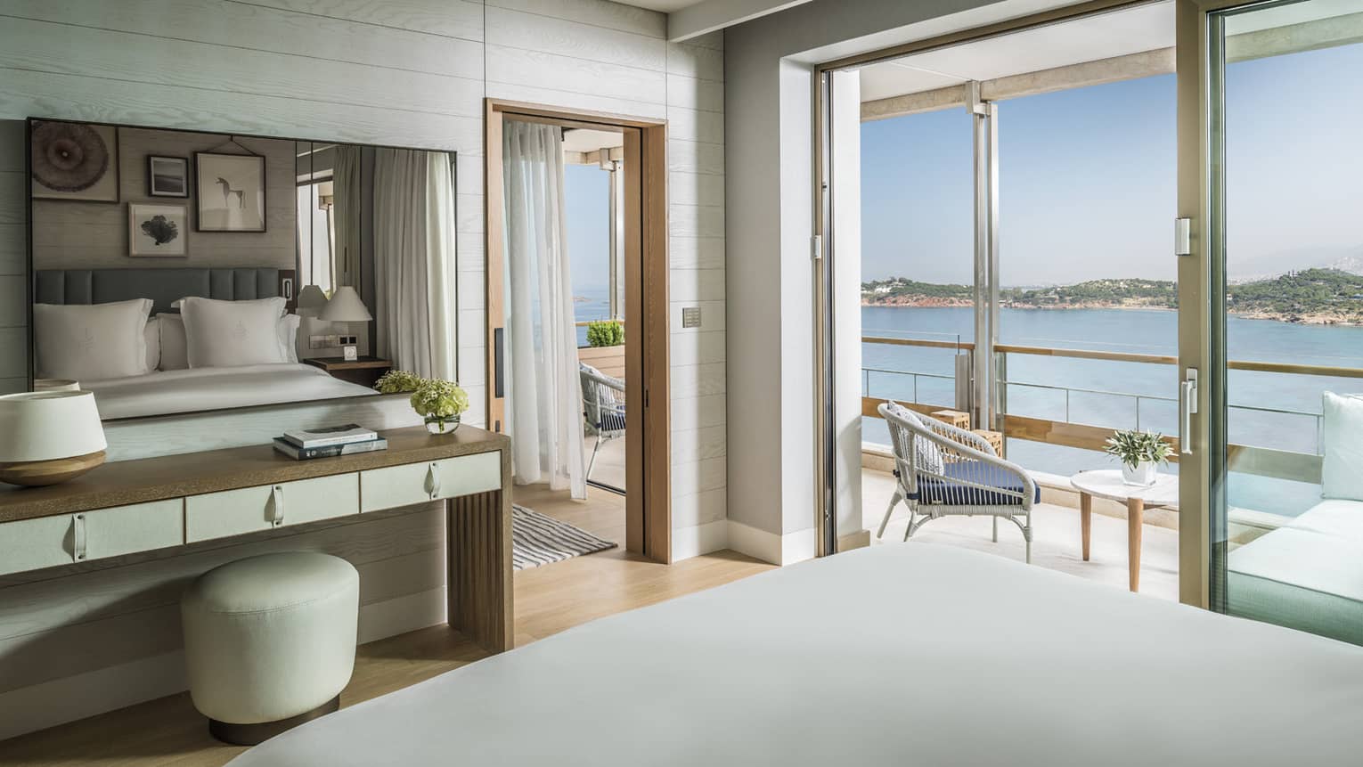 Arion Corner Suite hotel bed, tables, open balcony door with water views