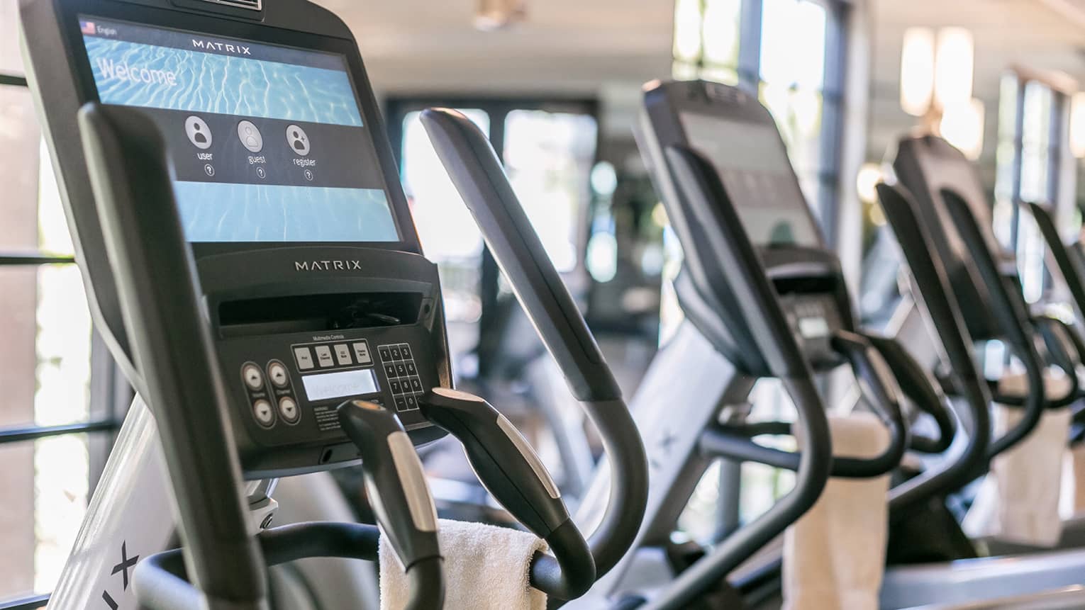 Close-up of Matrix cardio machine screens and handles in a row