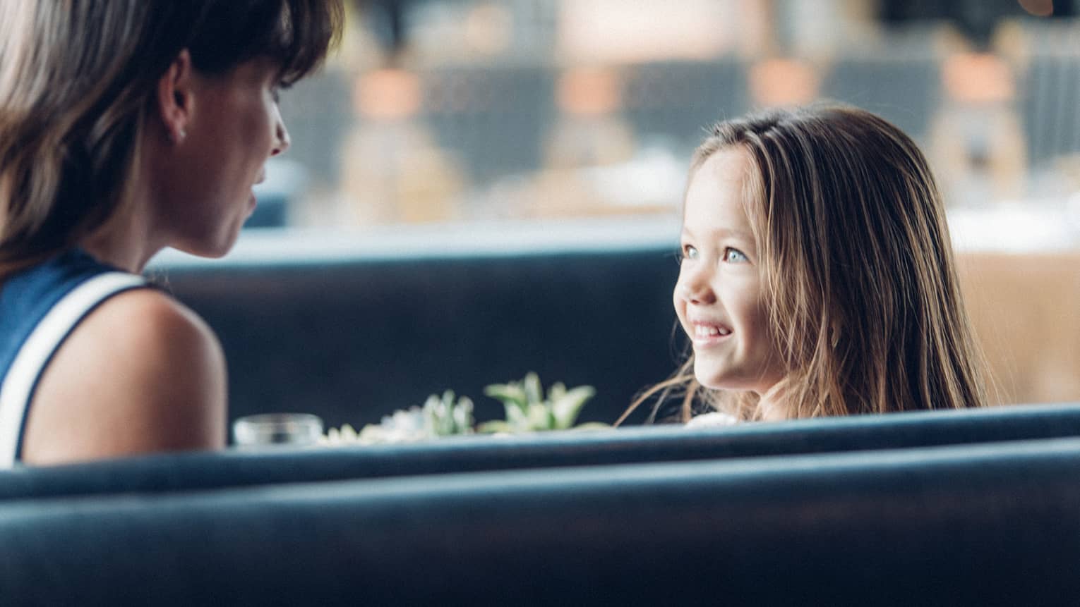 Woman in booth faces smiling, wide-eyed young girl