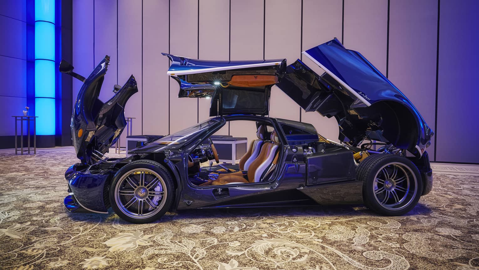 Modern convertible sports car with open hood, trunk and doors, in ballroom showroom