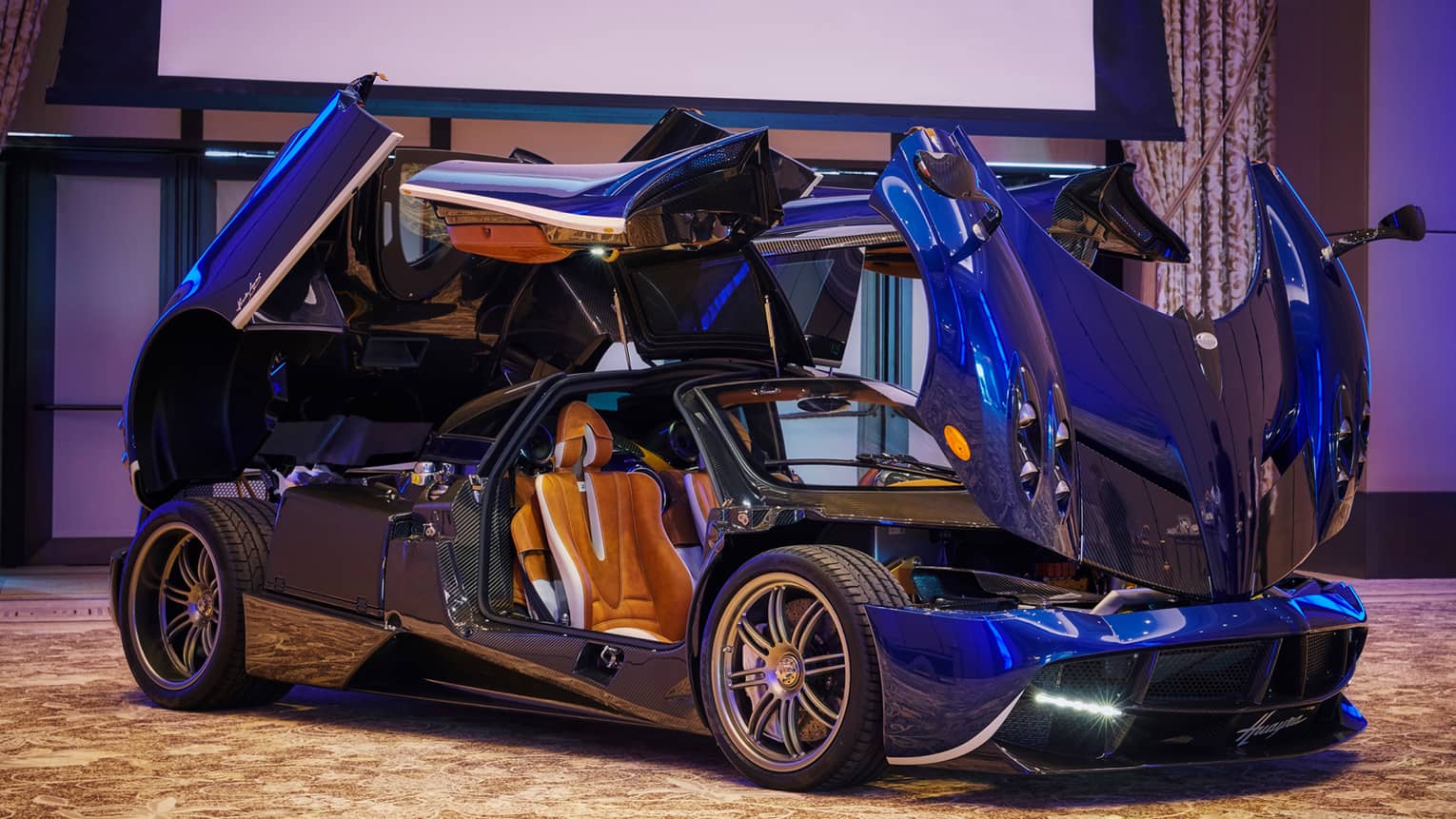 Modern convertible sports car with open hood, trunk and doors, in ballroom showroom