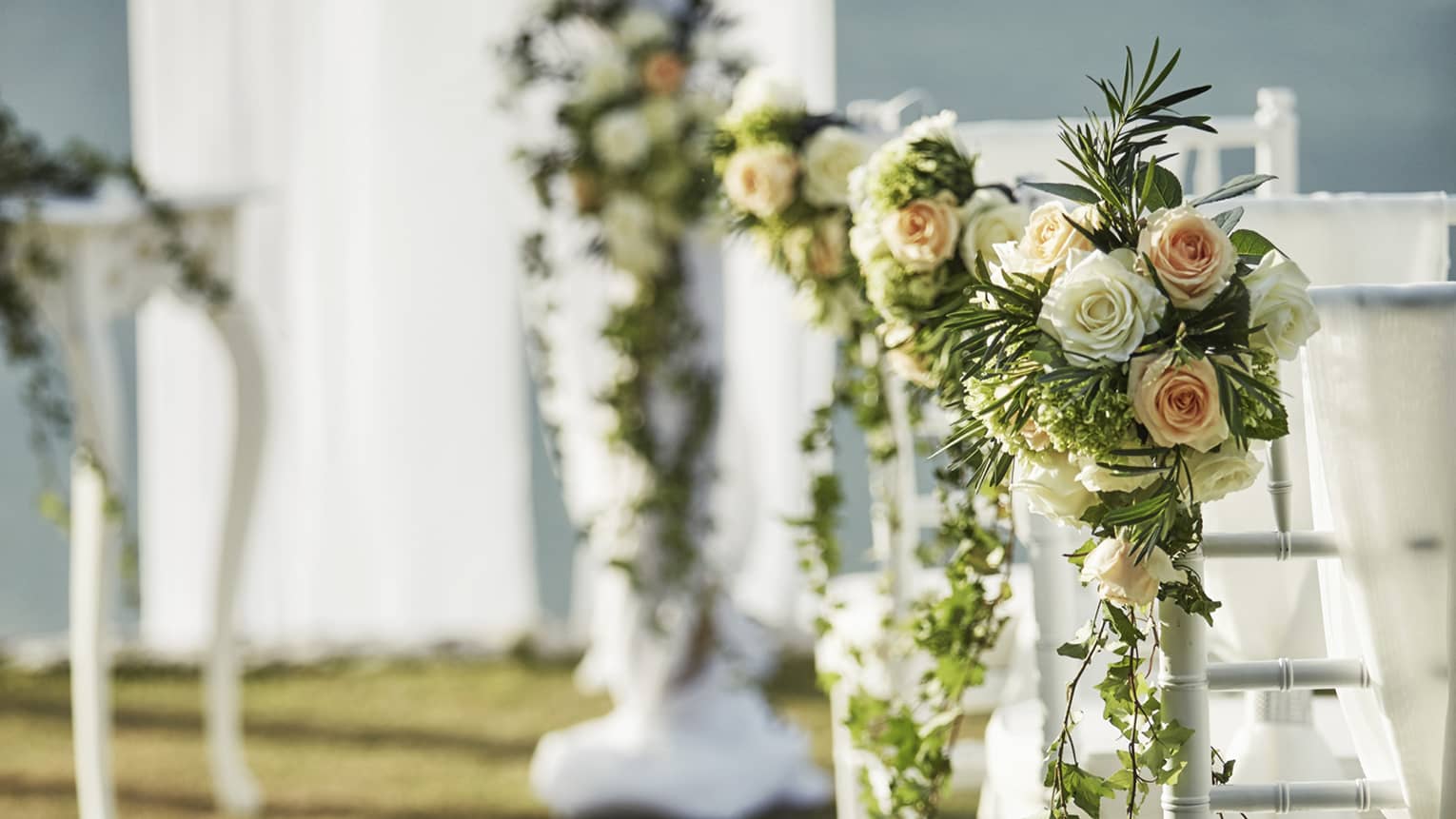Pink and white rose bouquets on wedding chairs, table
