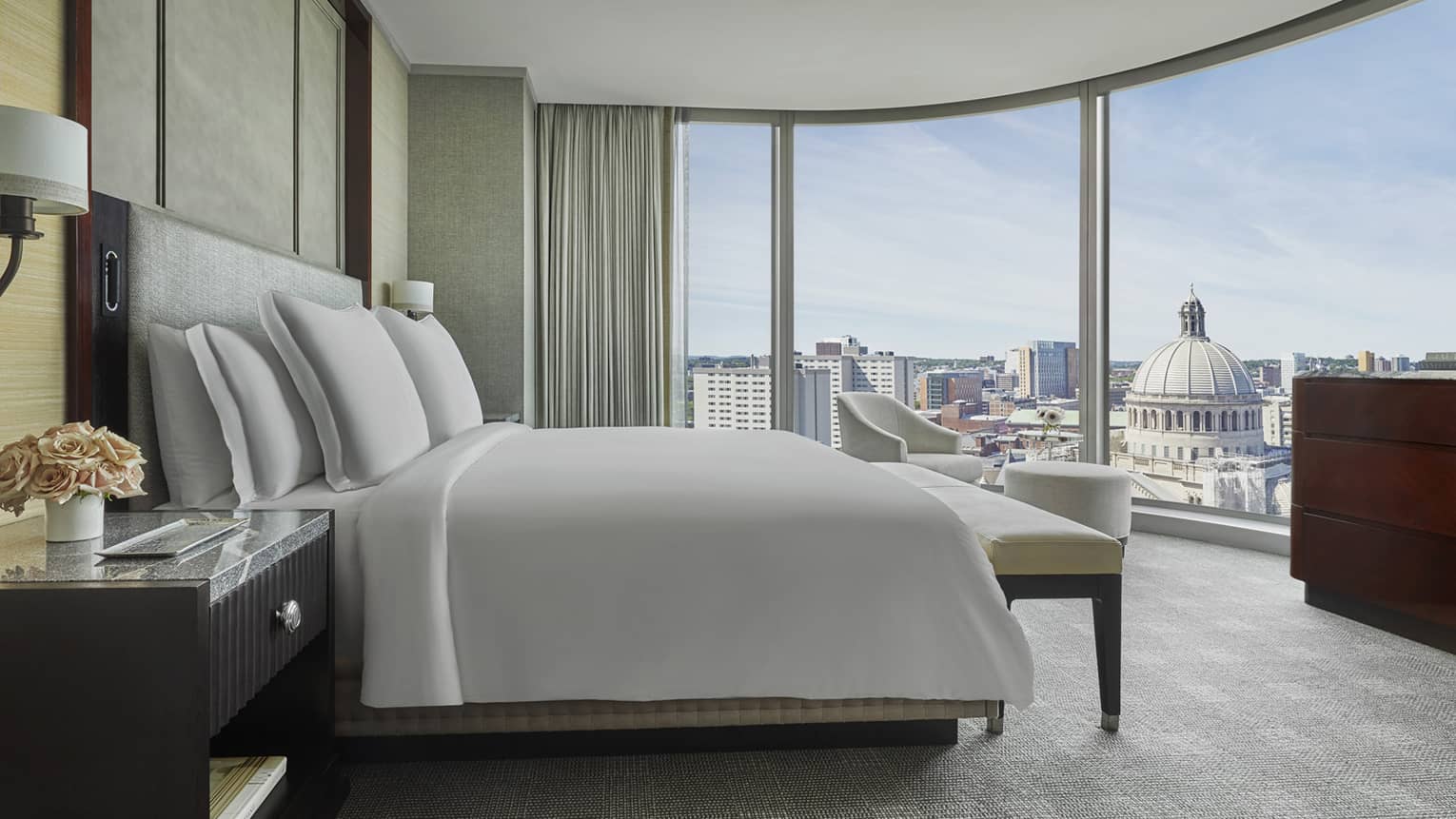 view of downtown boston skyline through floor to ceiling windows in a suite at the Hotel