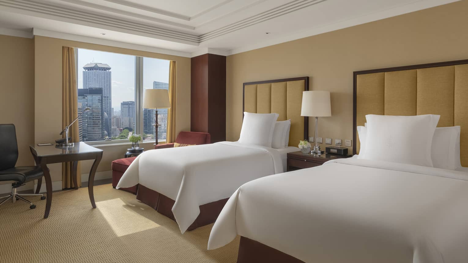 Hotel room with two single beds, leather headboards, table with chair and windowside chaise