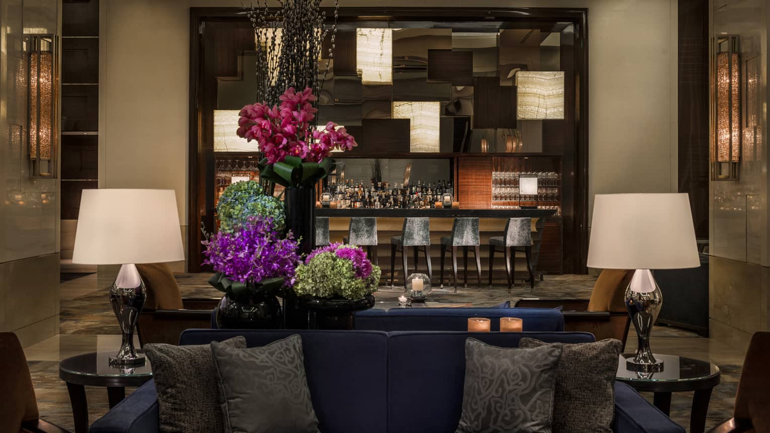 Opus Bar with grey stools behind lounge sofas, purple flowers