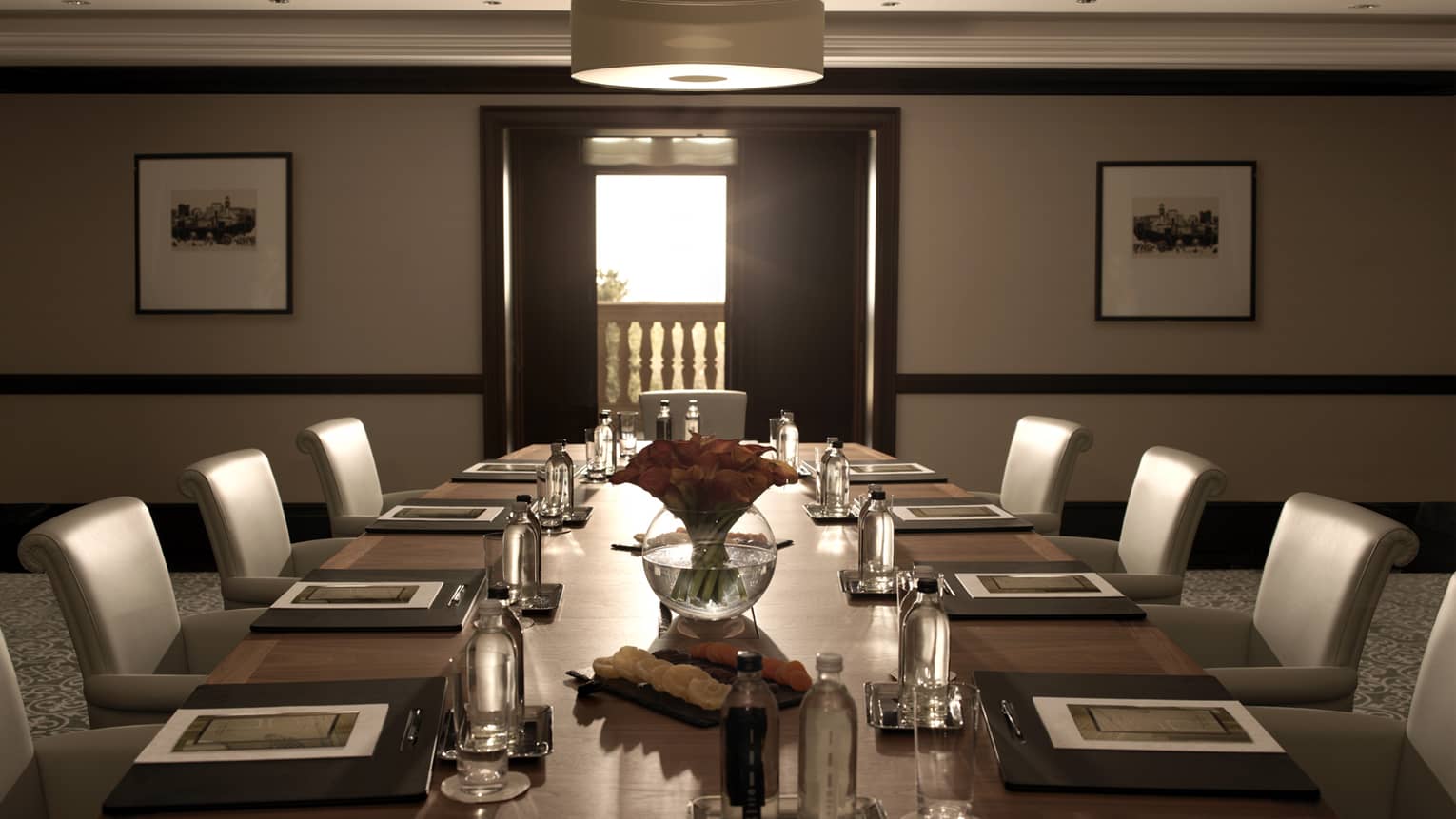 Sleek leather chairs around large, dark wood boardroom table set for business event 
