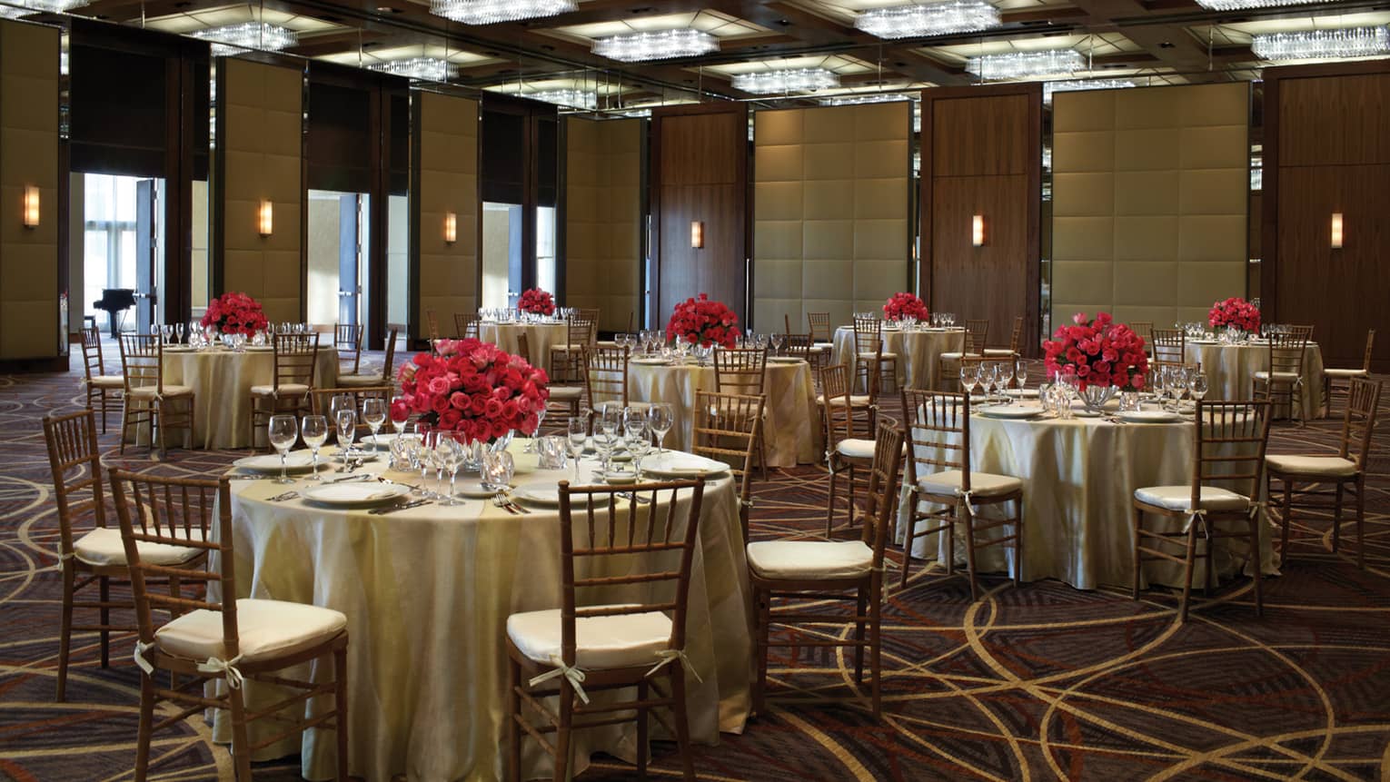 Grand Ballroom round banquet dining tables set with red flower centrepieces 