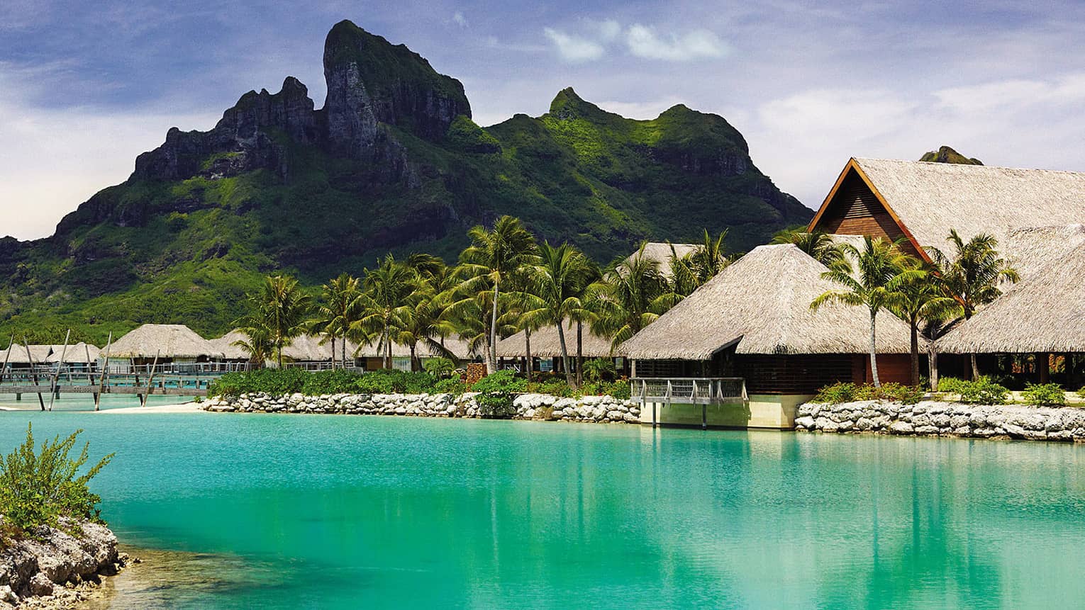 View over turquoise water to resort building, mountain