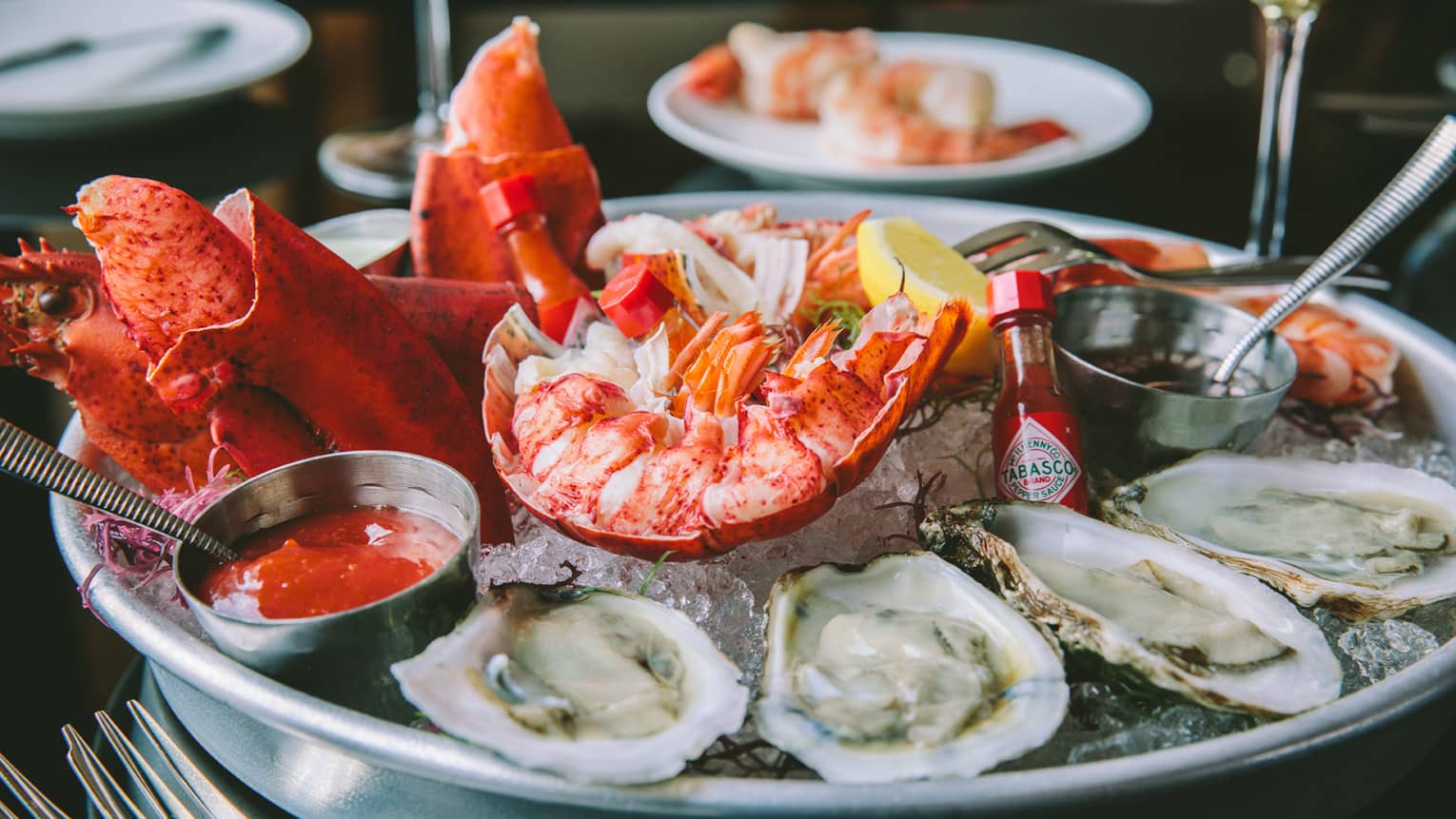Fresh oysters, shrimp and lobster claws on platter with sauces 