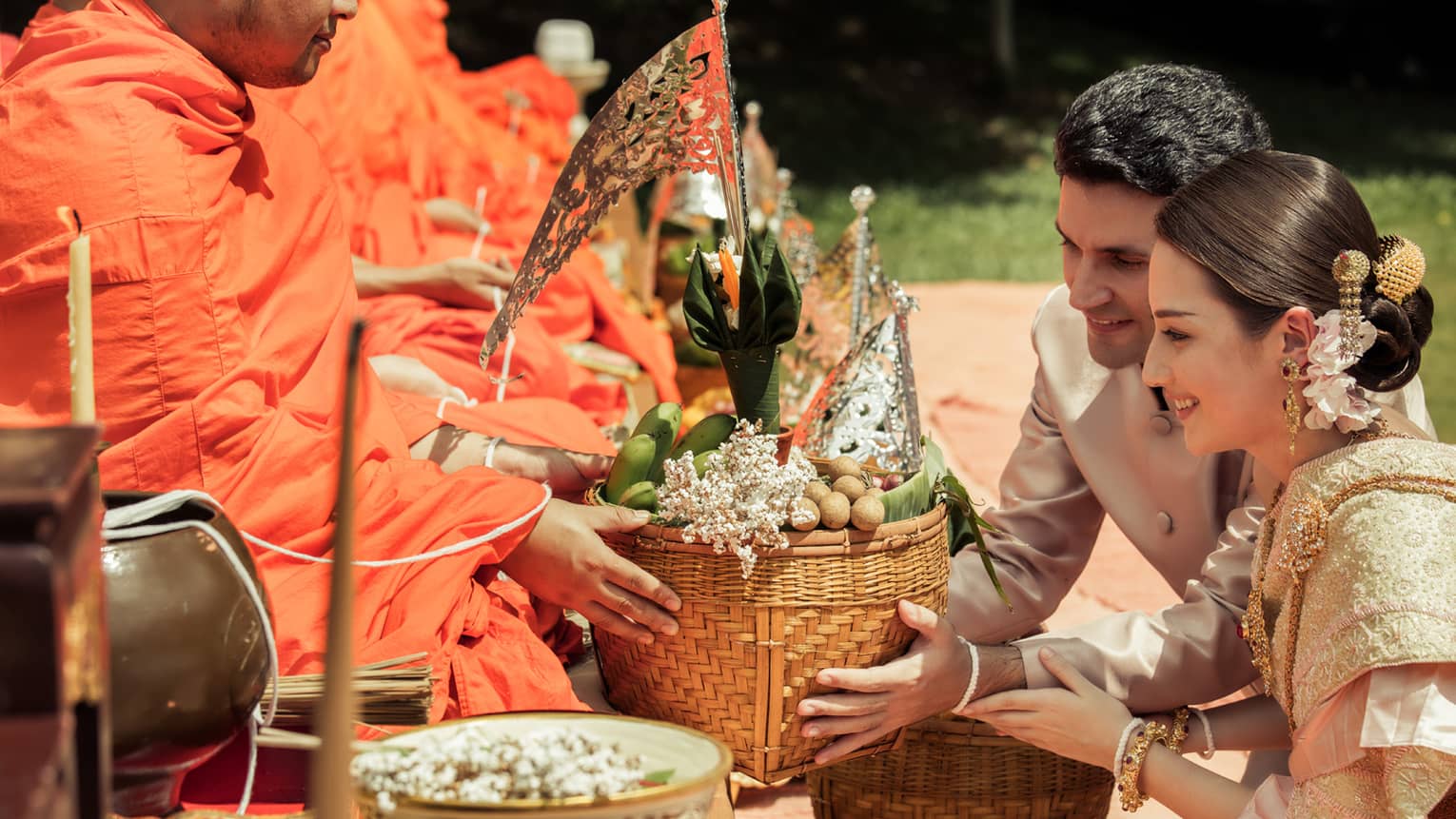 Couple holds boat shaped basket of fruit during Thai wedding ceremony