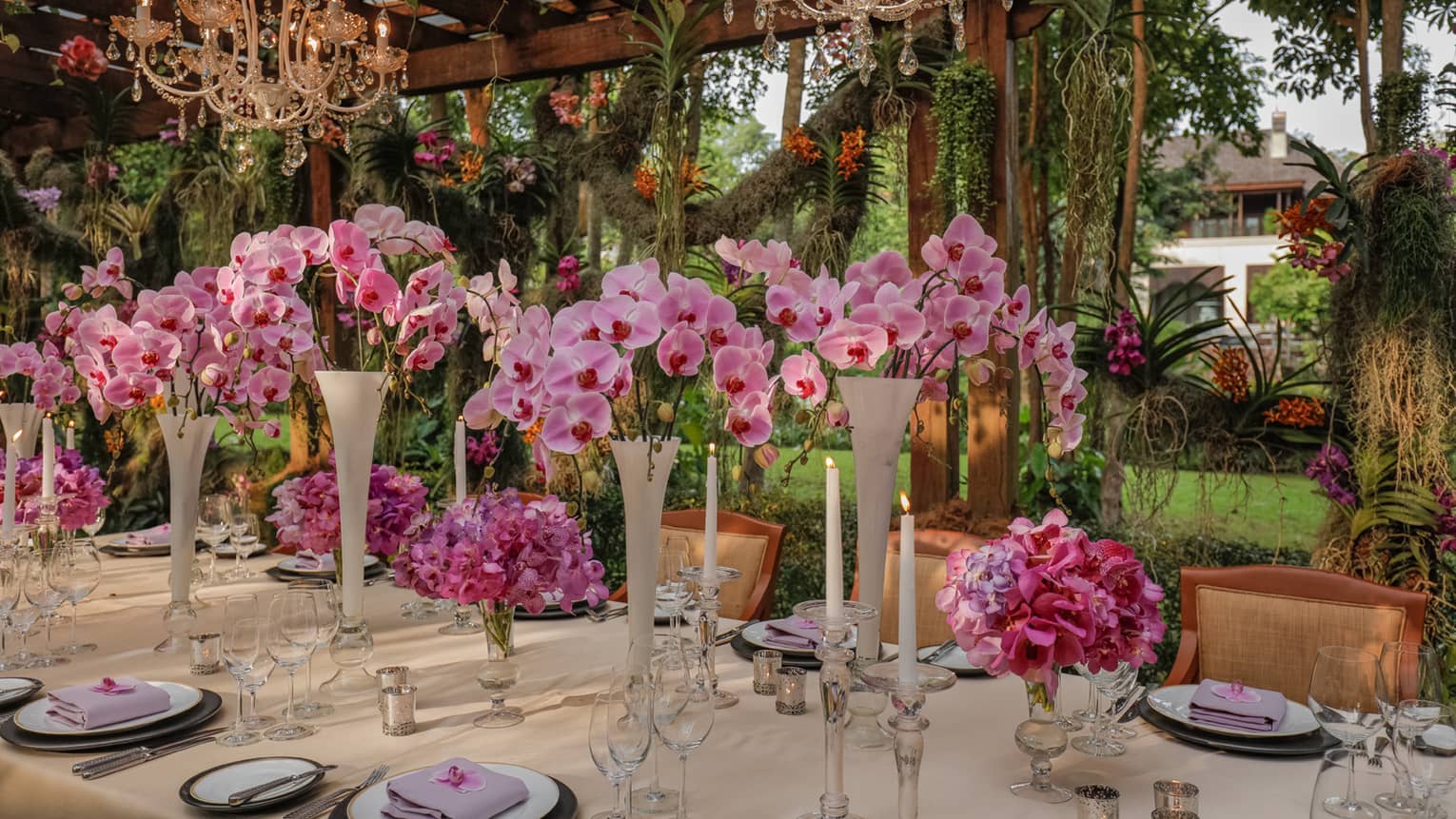 Tall vases with white orchids on outdoor wedding dining table