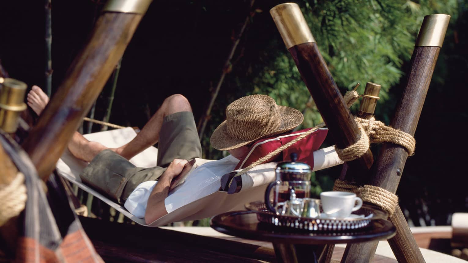 Man takes a nap in a handmade hammock with a straw sunhat shielding his face