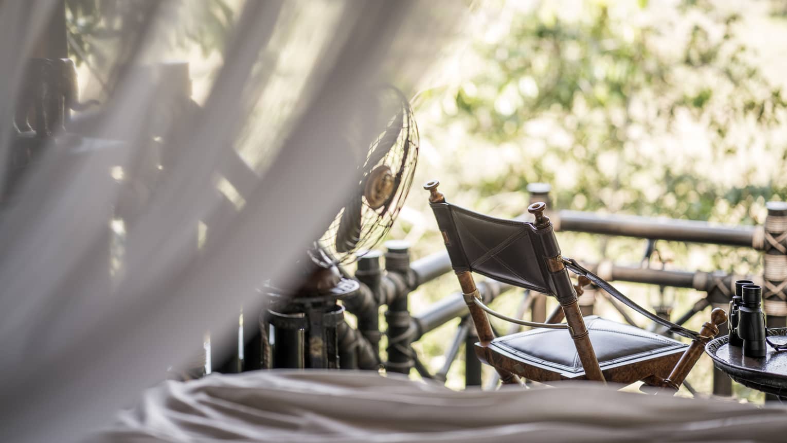 Wood chair at window, view from sheer white net on bed