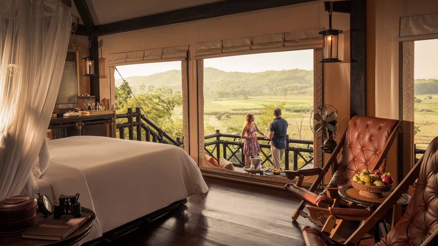 Couple enjoys cocktails at Tent Sundowner, overlooking fields and mountains