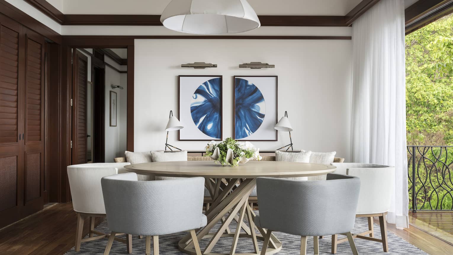 Grey and white mid-century style dining chairs and round dining table by floor-to-ceiling window