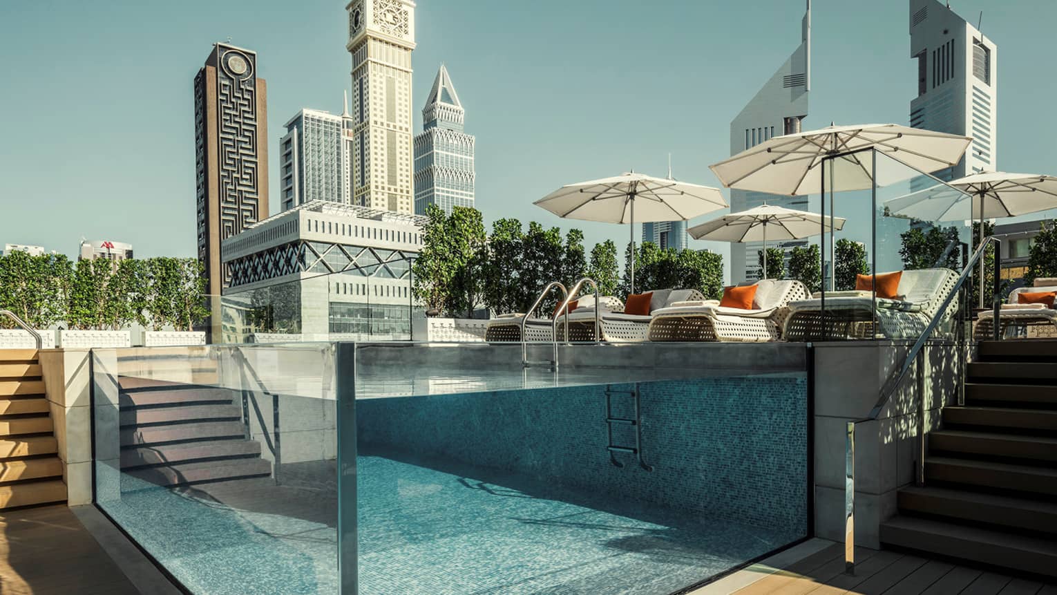 Raised glass plunge pool by stairs on patio deck, lounge chairs, umbrella