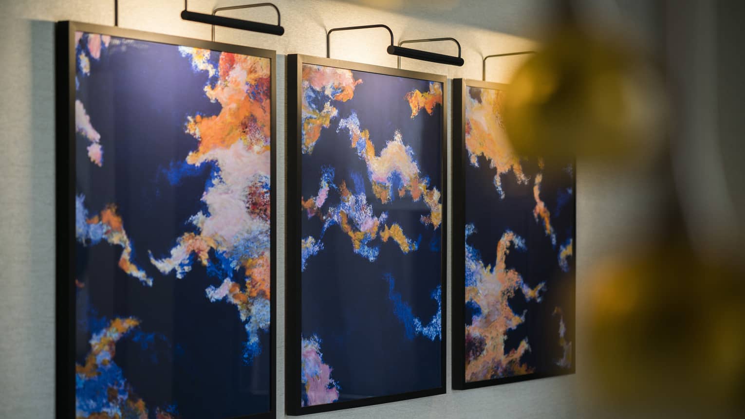 Brightly-coloured, three panel abstract painting on wall