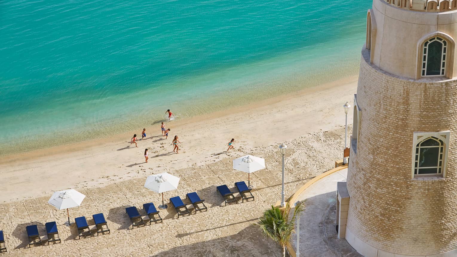 Aerial view of people on beach, row of lounge chairs, beach umbrella