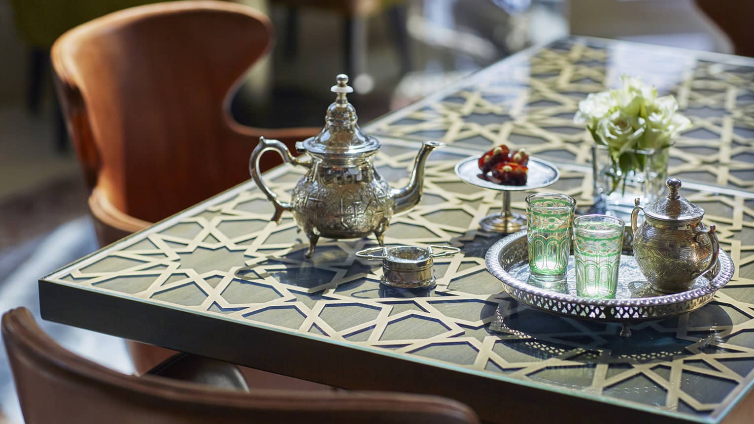 Small Moroccan-style tea pot and colourful glasses on silver tray on table