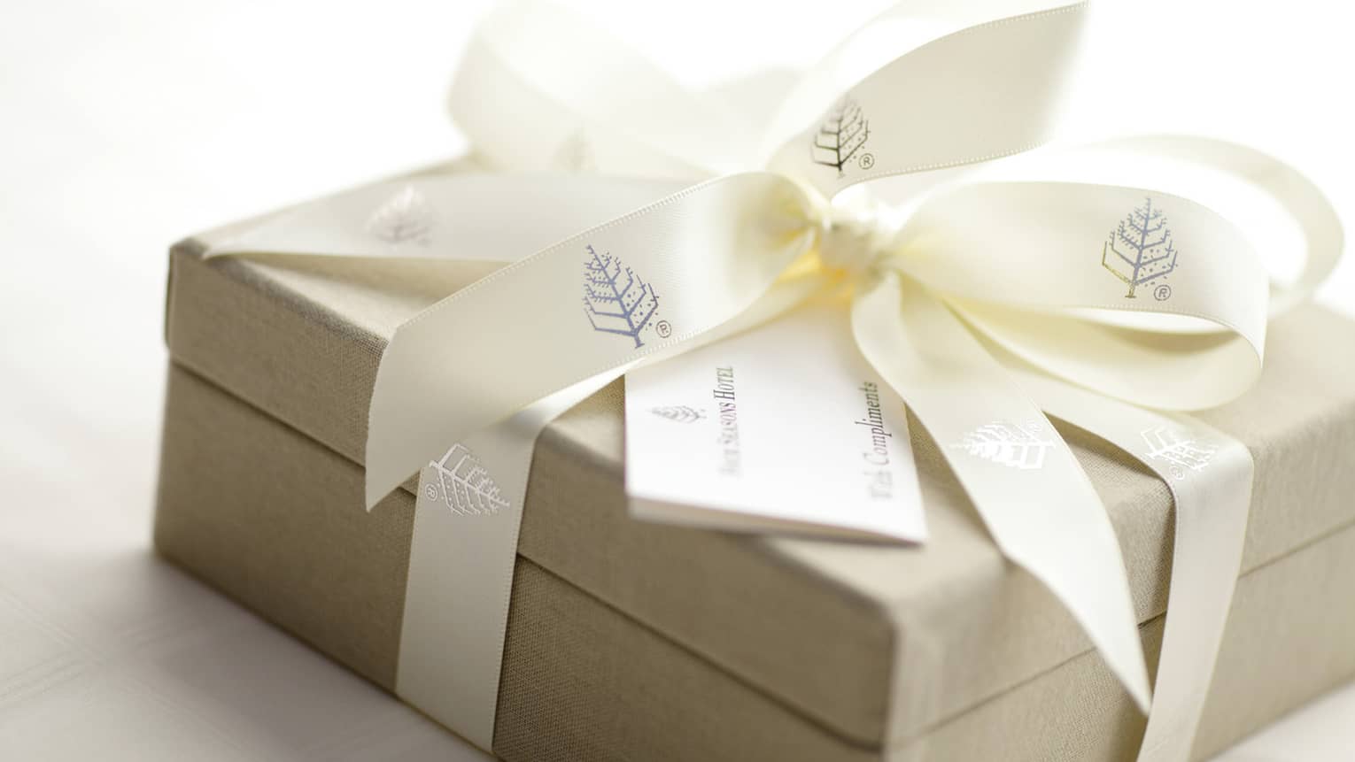 Gift box wrapped up with Four Seasons branded ribbon with a card