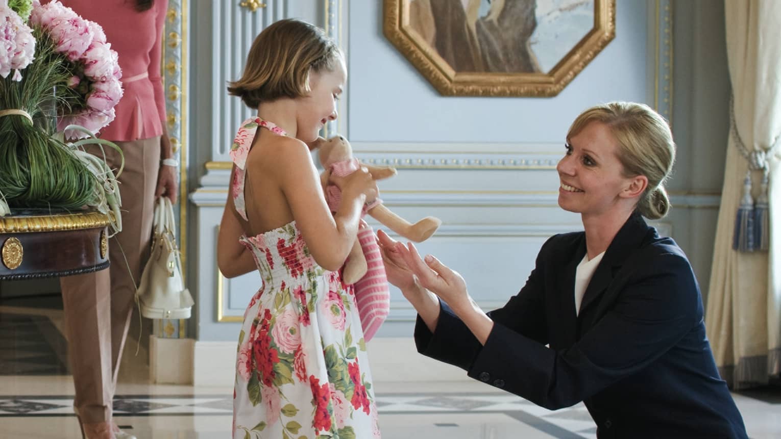 Friendly female concierge plays with little girl and her doll