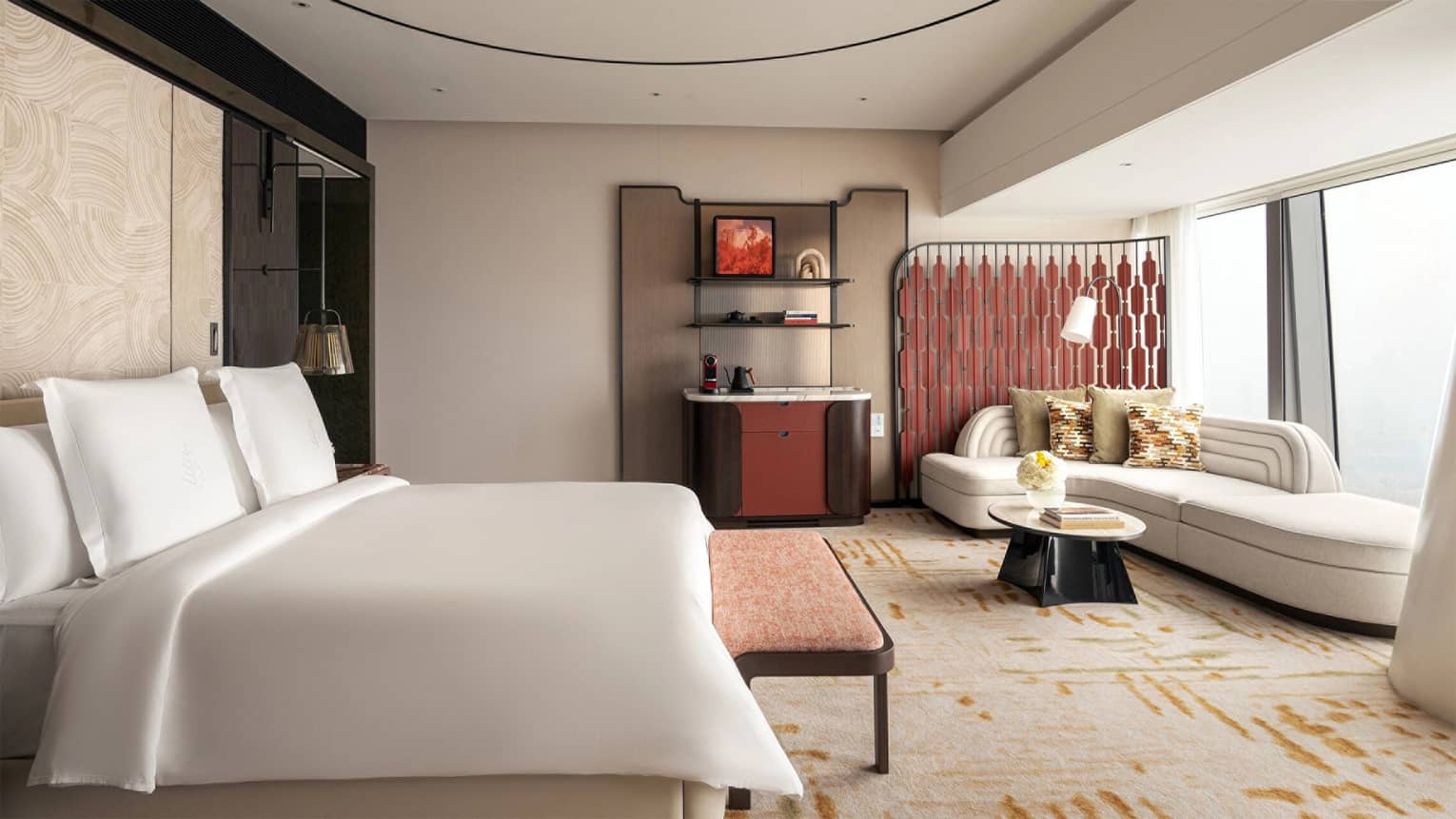 Contemporary hotel room with king bed, wet bar and sofa by the window