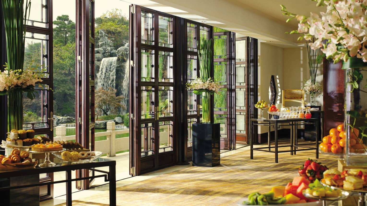 Pre-function space with buffet food tables, open glass doors to patio and waterfall