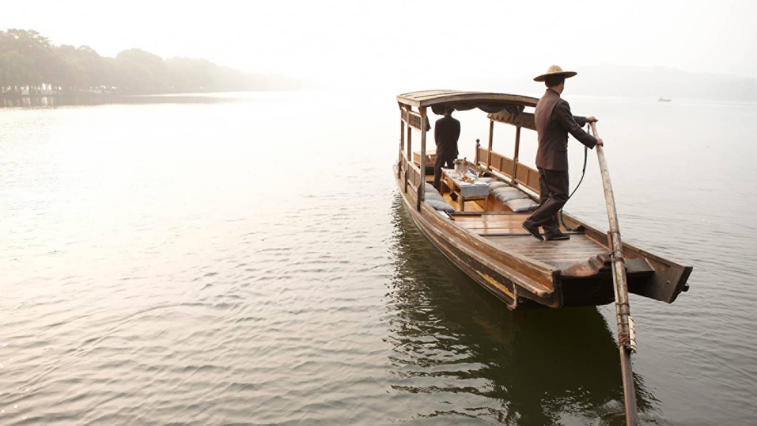 Hozugawa River boat ride, man wearing hat on back of wood boat 